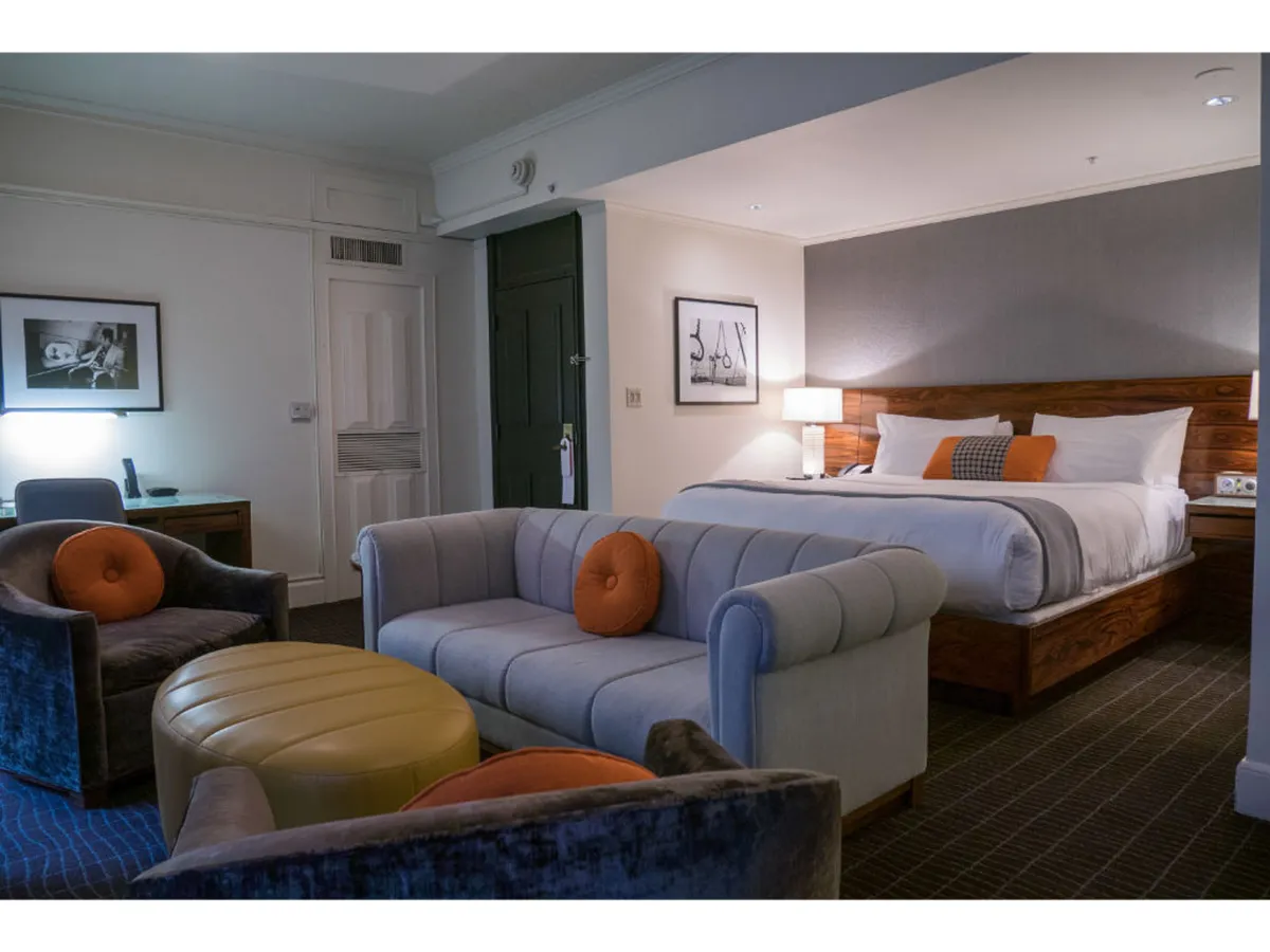 This image captures a spacious suite featuring a cozy bed, elegant sofa, accent chairs, and a coffee table. The atmosphere is relaxed and inviting, perfect for unwinding after a city adventure. The layout and comfort of the furnishings suggest a space where guests—and their pets—can lounge and feel at home.