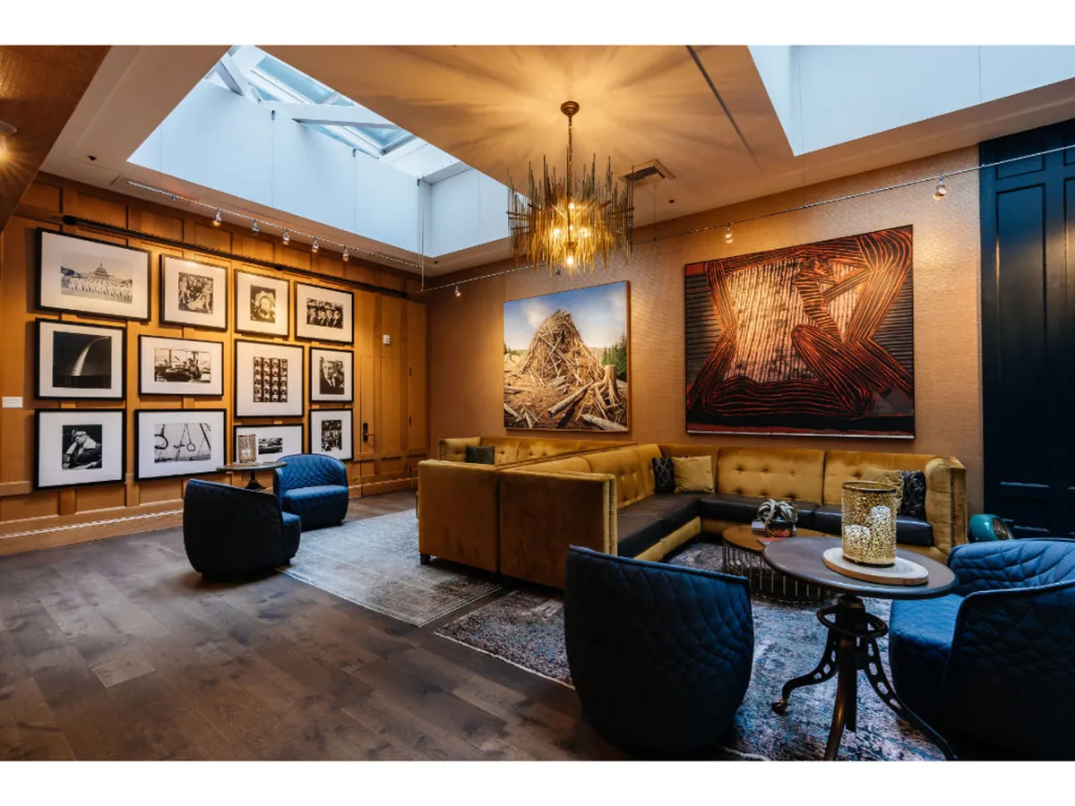 A stylish gallery area featuring a prominent artwork on the wall, modern sofa seating, and sophisticated chandelier lighting. The gallery wall serves as a focal point for immersive art appreciation and gatherings.
