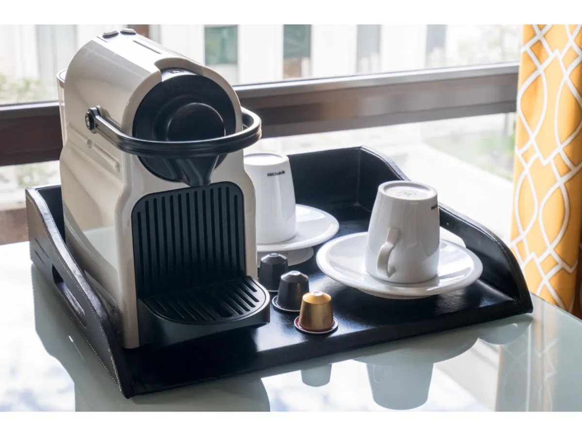 A close-up of a Nespresso machine, coffee cups, and a selection of coffee capsules arranged on a sleek tray, ready for guests’ enjoyment. The setup exudes a sense of thoughtful hospitality and urban sophistication.